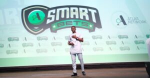 Emmanuel Acquah delivering a presentation on ACEYE's REF Index report at the Atlas Network's Smart Bets competition stage, with the Smart Bets logo displayed prominently in the background.